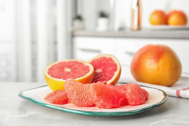 Plate with ripe grapefruits on table against blurred background