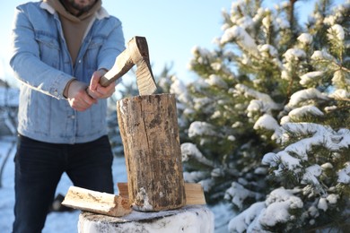 Photo of Man chopping wood with axe outdoors on winter day, closeup. Space for text