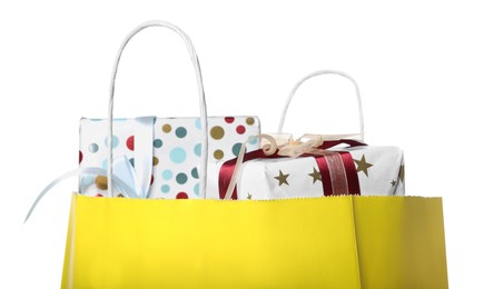 Yellow paper shopping bag full of gift boxes on white background, closeup