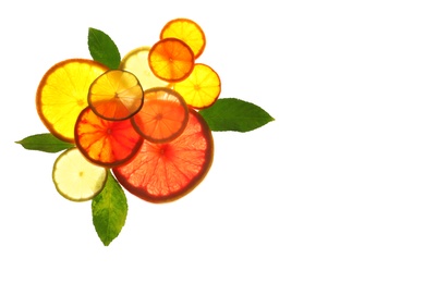 Illuminated slices of citrus fruits and leaves on white background, top view