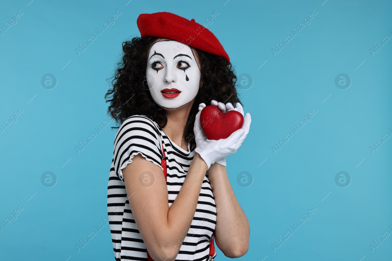 Photo of Funny mine with red heart figure posing on light blue background