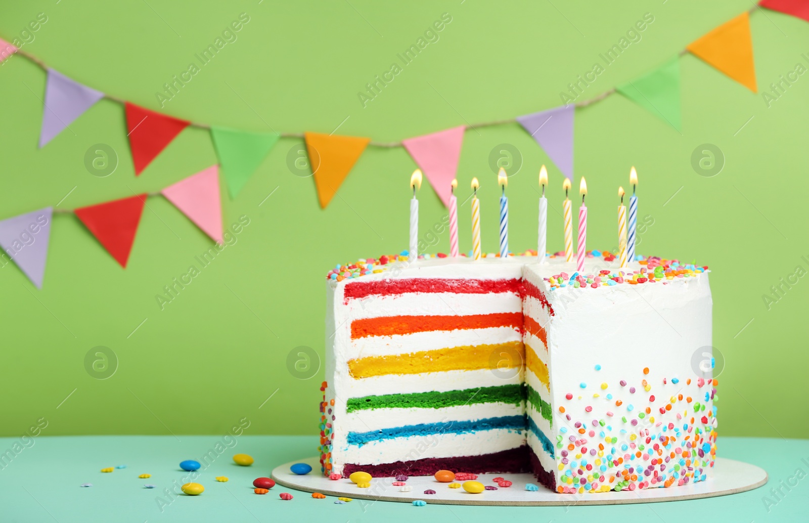 Photo of Delicious rainbow cake with candles on color background