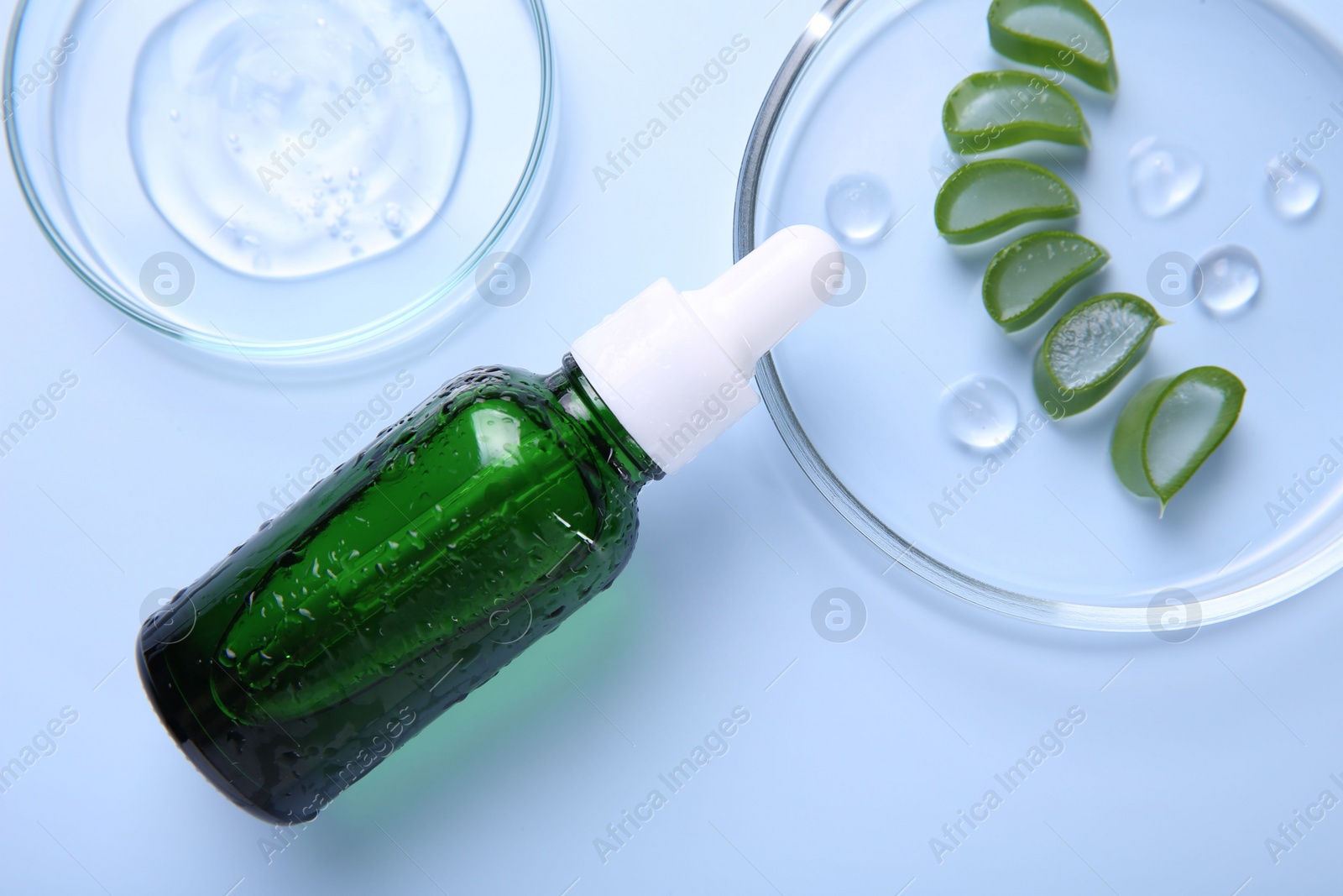 Photo of Cut aloe vera, bottle and cosmetic gel on light blue background, flat lay