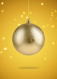 Image of Beautiful golden Christmas ball hanging on orange background