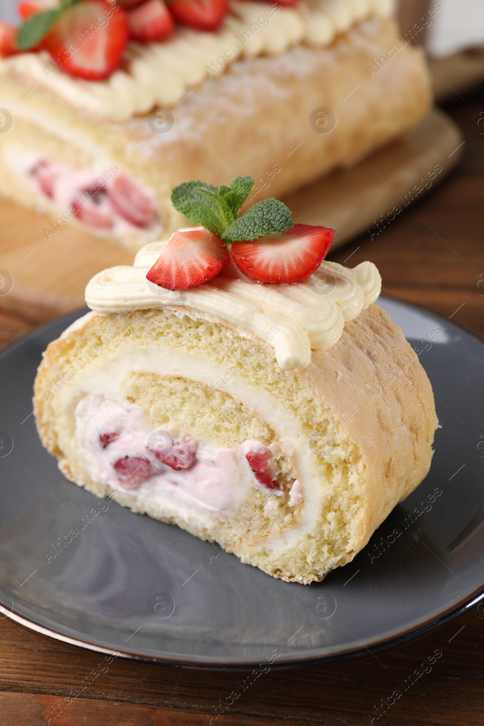 Photo of Delicious cake roll with strawberries and cream on gray plate