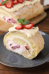 Photo of Delicious cake roll with strawberries and cream on gray plate