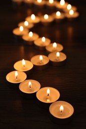 Burning candles on wooden table in darkness