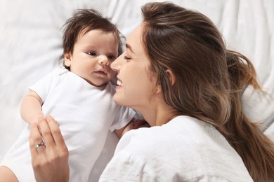 Mother and her little baby lying on bed, top view