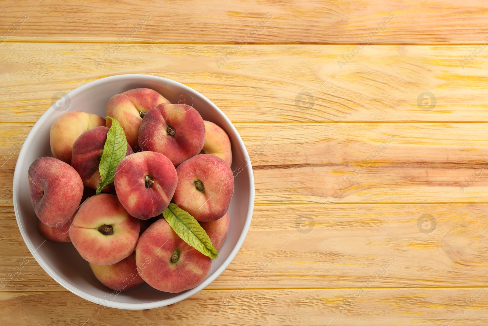 Photo of Fresh ripe donut peaches on wooden table, top view. Space for text