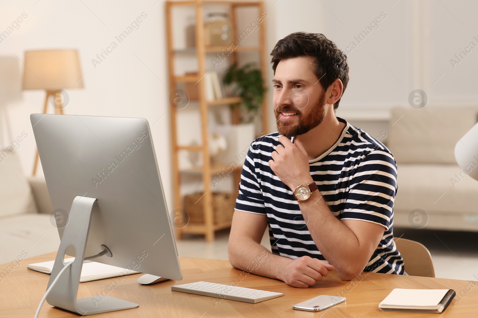 Photo of Home workplace. Happy man having video conference at wooden desk in room