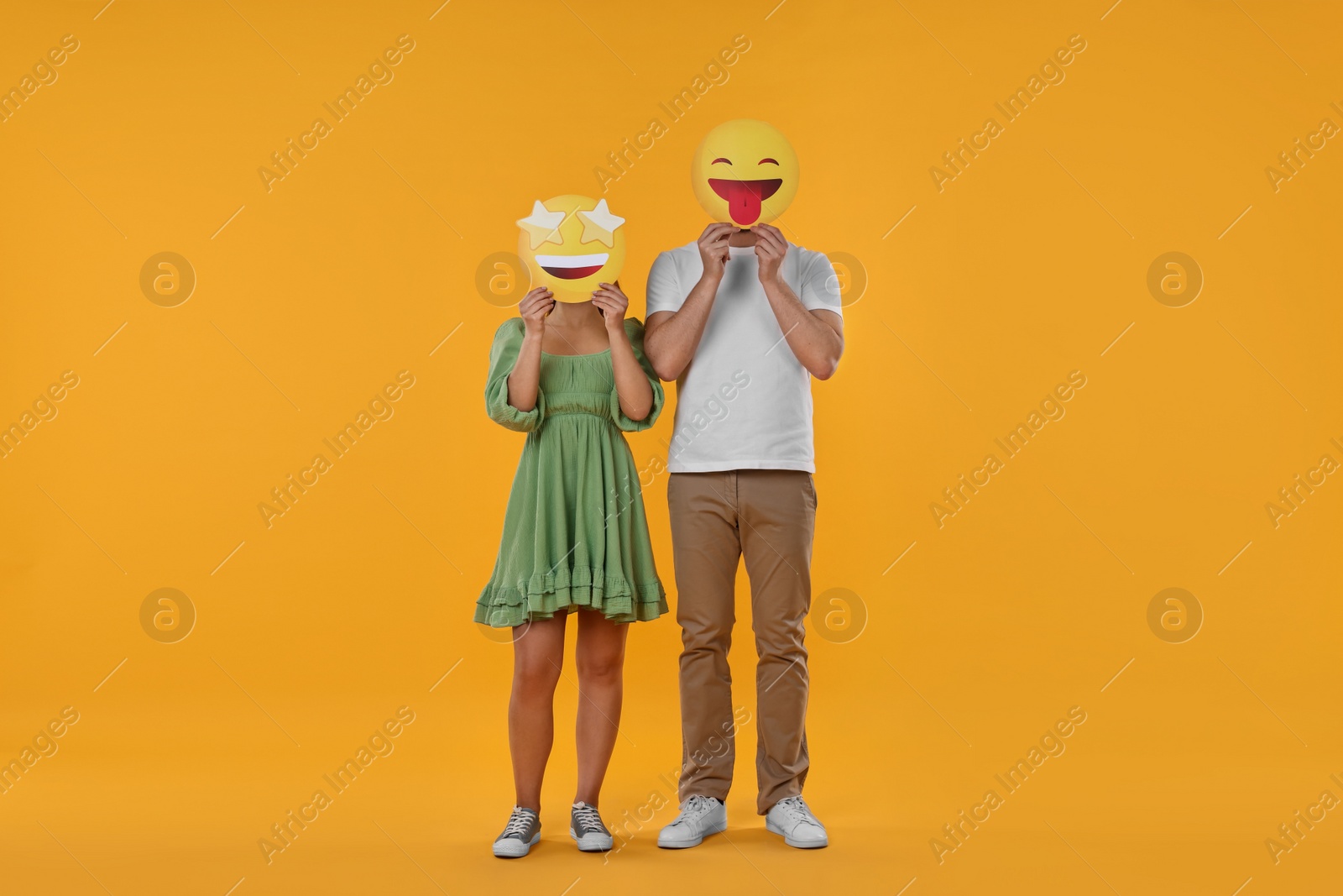 Photo of People covering faces with emoticons on yellow background