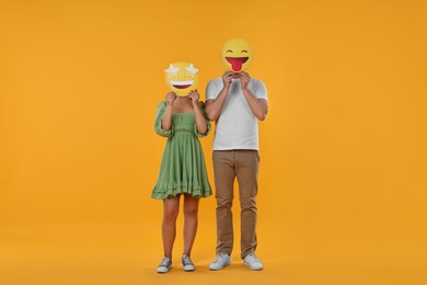 People covering faces with emoticons on yellow background