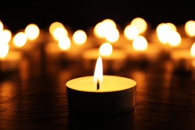 Photo of Burning candle on black table, closeup. Memory day