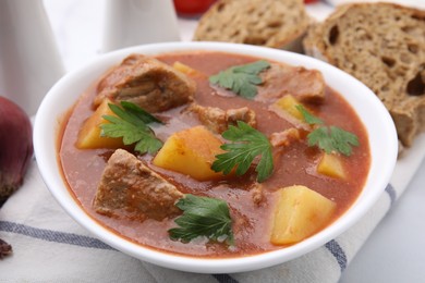 Photo of Delicious goulash in bowl on white table, closeup