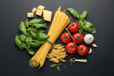 Photo of Different types of pasta, spices and products on black background, flat lay