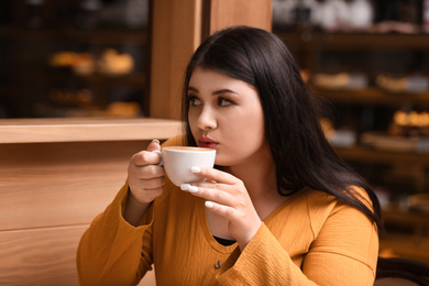 Photo of Beautiful overweight woman in cafe. Plus size model