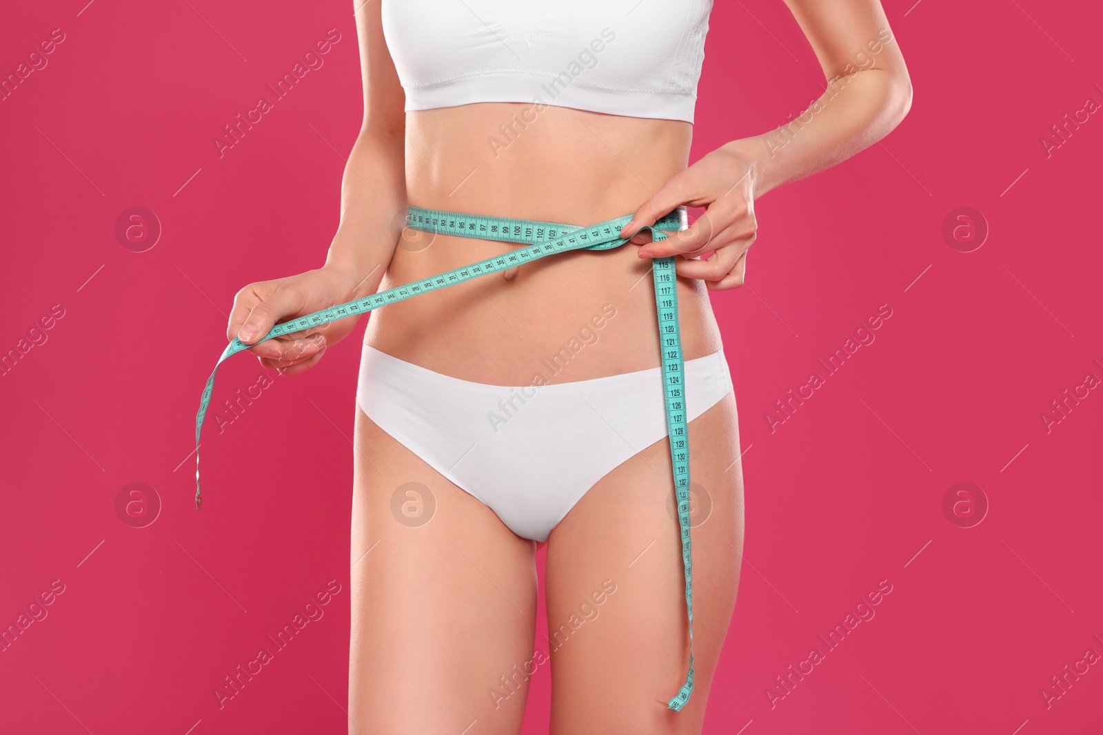 Photo of Slim young woman with smooth gentle skin in underwear measuring body on color background, closeup