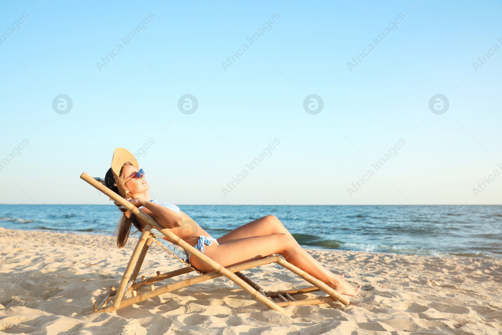 Photo of Young woman relaxing in deck chair on beach