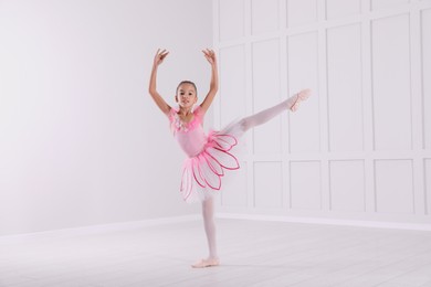Beautifully dressed little ballerina dancing in studio