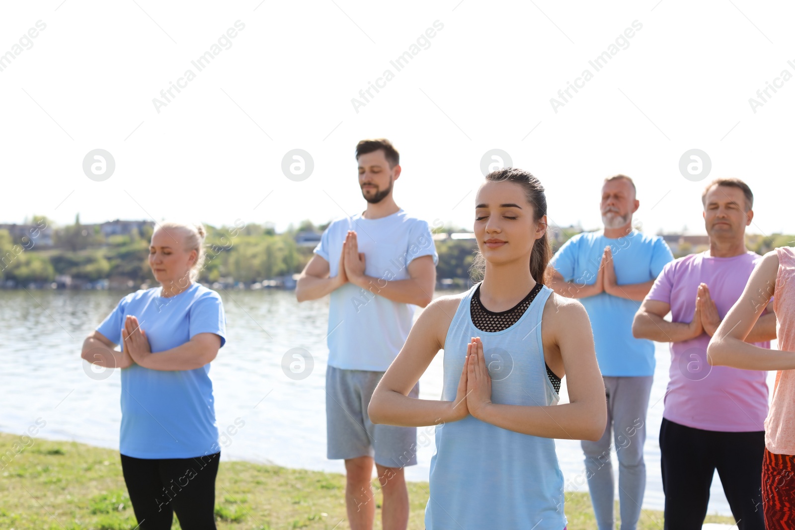 Photo of Group of people practicing yoga near river on sunny day