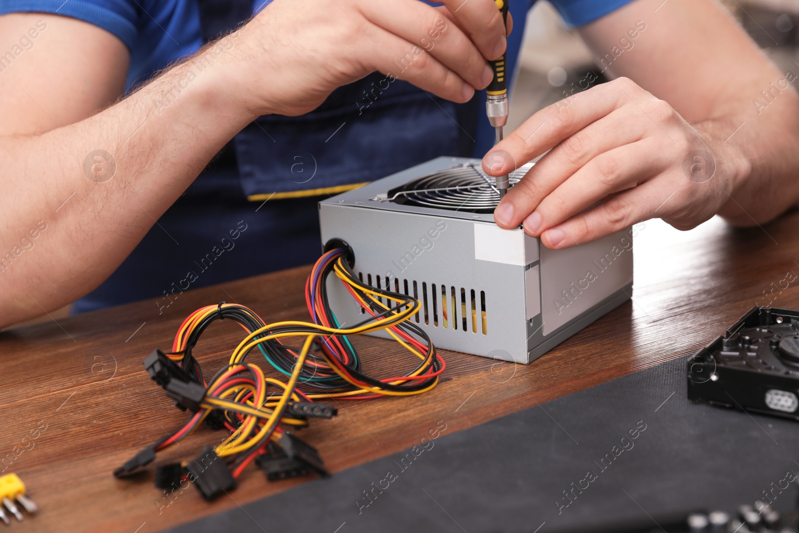 Photo of Male technician repairing power supply unit at table, closeup