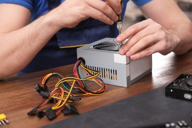 Male technician repairing power supply unit at table, closeup