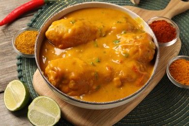 Photo of Tasty chicken curry and ingredients on wooden table