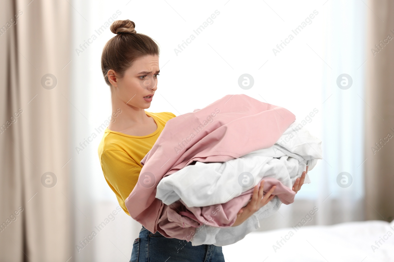 Photo of Woman holding pile of dirty laundry indoors