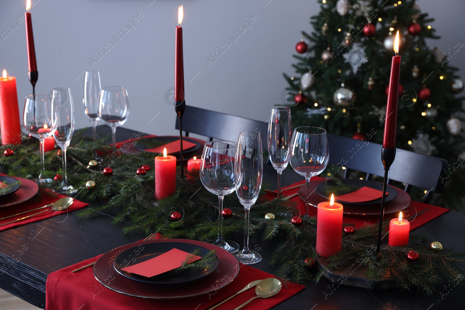 Photo of Elegant Christmas table setting with dishware and burning candles in festively decorated room