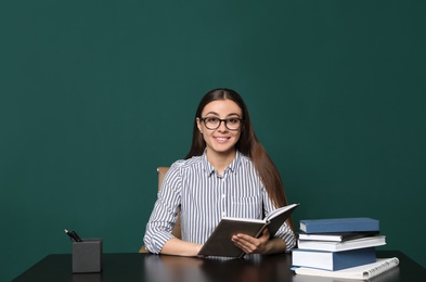 Photo of Portrait of young teacher at table against green background