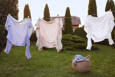 Clean clothes drying near wicker bag in backyard