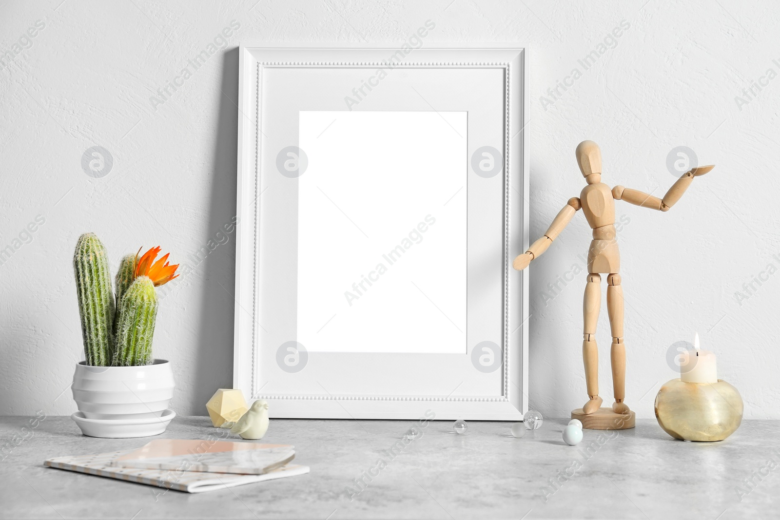 Photo of Mockup of blank frame and cactus on table