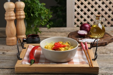 Photo of Stir-fry. Tasty noodles with vegetables and meat in bowl served on wooden table