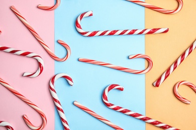 Flat lay composition with tasty candy canes on color background