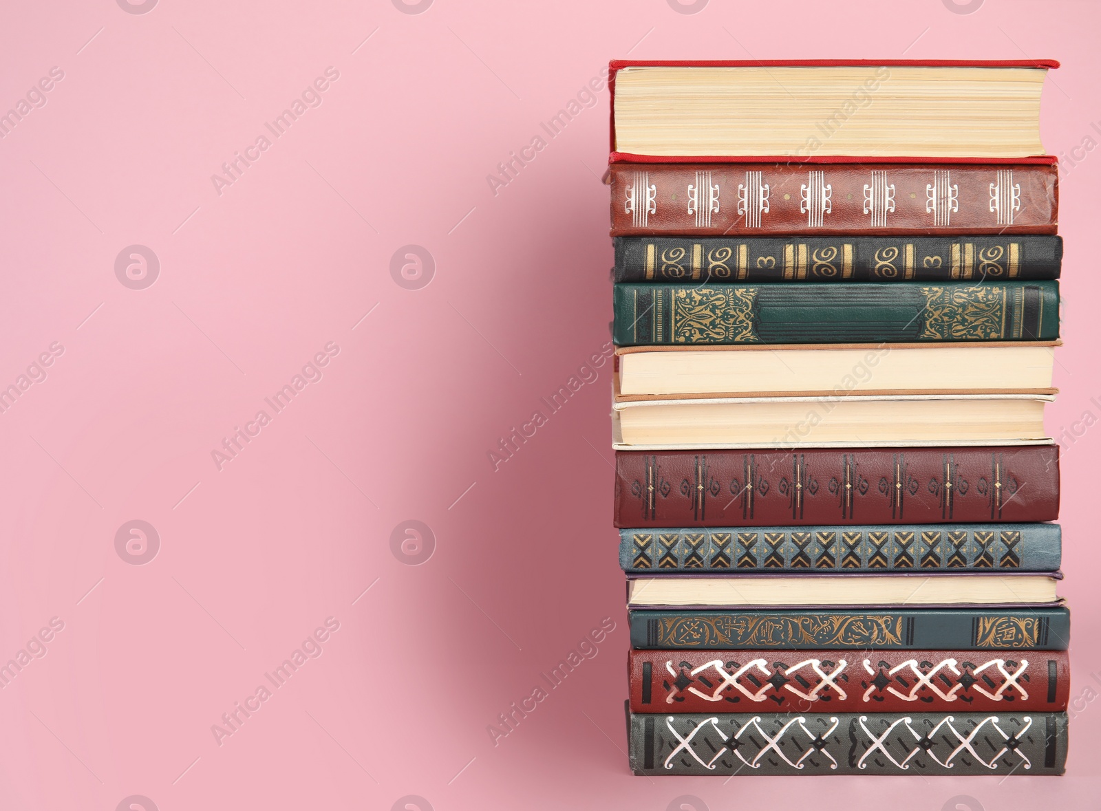 Photo of Stack of hardcover books on pink background. Space for text