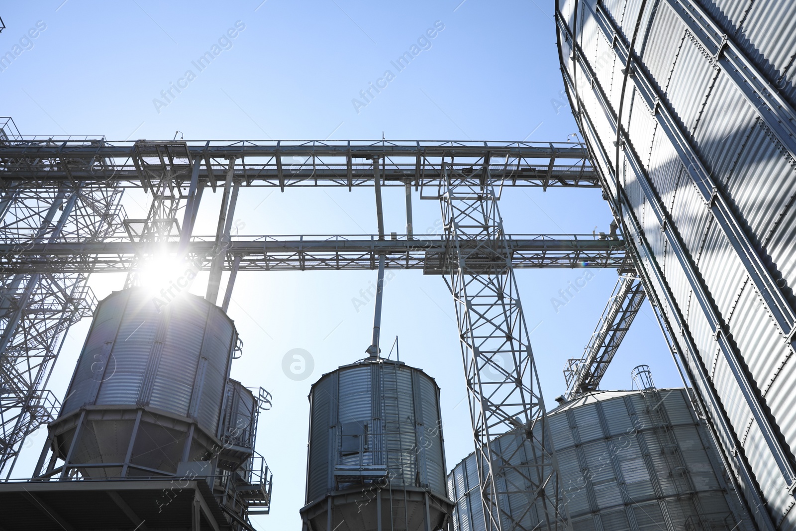 Photo of Modern granaries for storing cereal grains against blue sky, low angle view