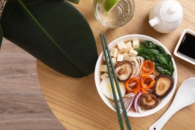 Delicious vegetarian ramen served on wooden table, flat lay. Noodle soup