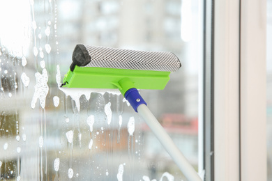 Photo of Cleaning window with squeegee and detergent at home