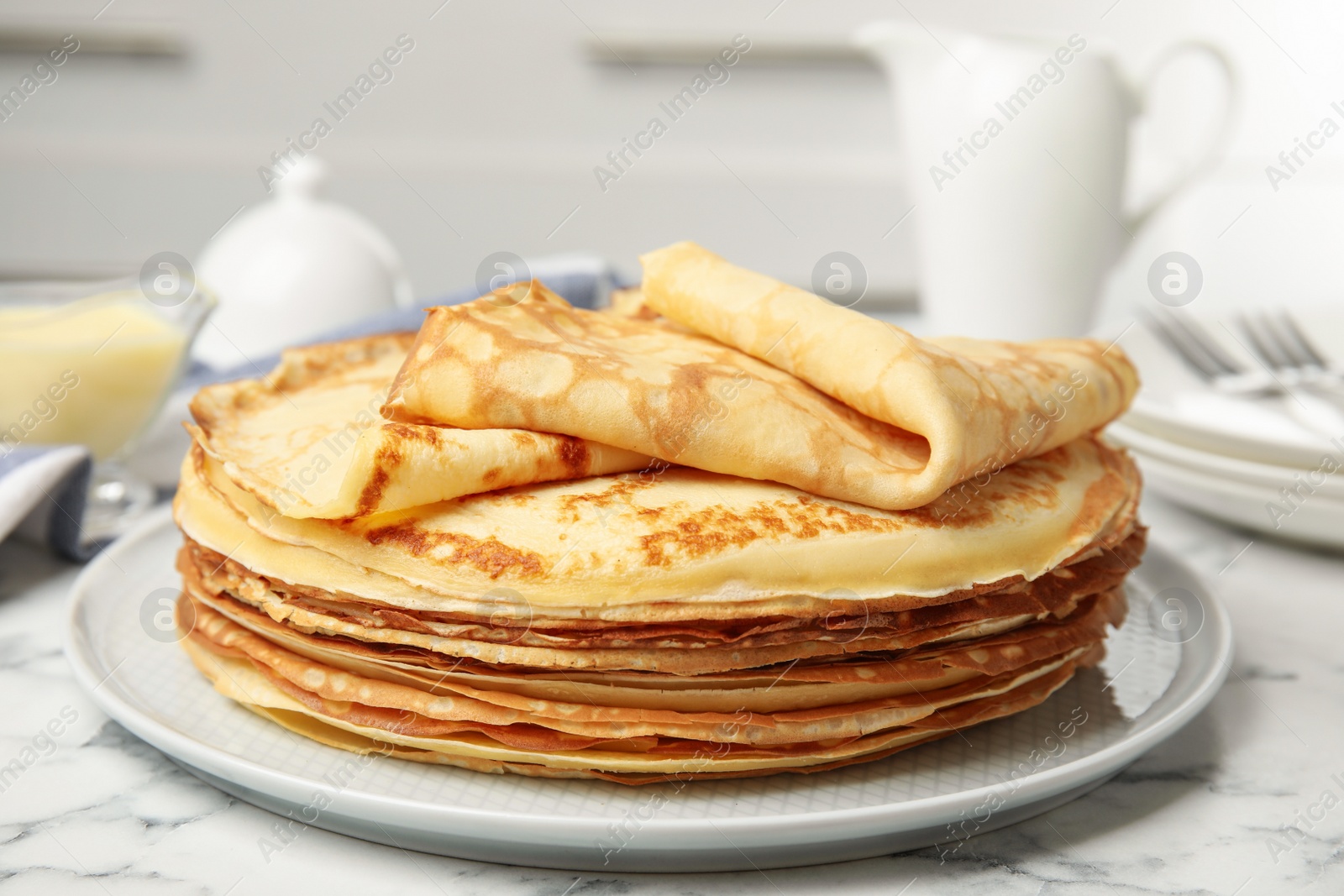 Photo of Stack of fresh thin pancakes on white marble table