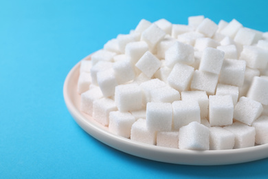 Photo of Refined sugar cubes on light blue background, closeup