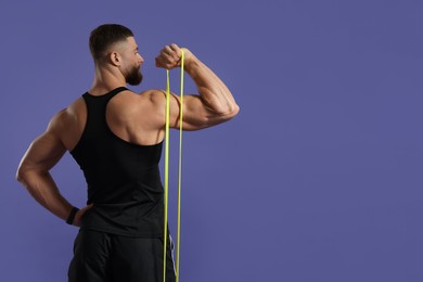 Photo of Muscular man exercising with elastic resistance band on purple background, back view. Space for text