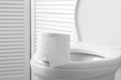New paper roll on toilet bowl in bathroom