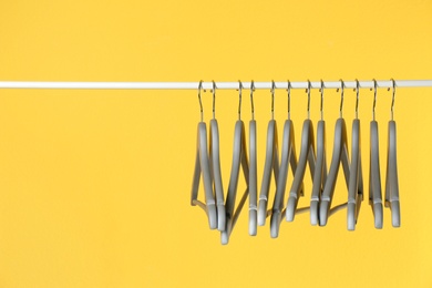 Metal rack with clothes hangers on color background, space for text