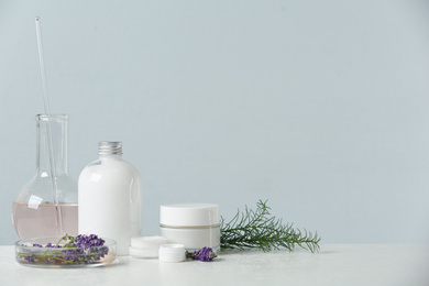 Photo of Herbal cosmetic products, laboratory glassware and ingredients on white table, space for text