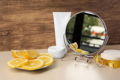 Photo of Lemon face wash. Fresh citrus fruits, personal care products and mirror on beige table