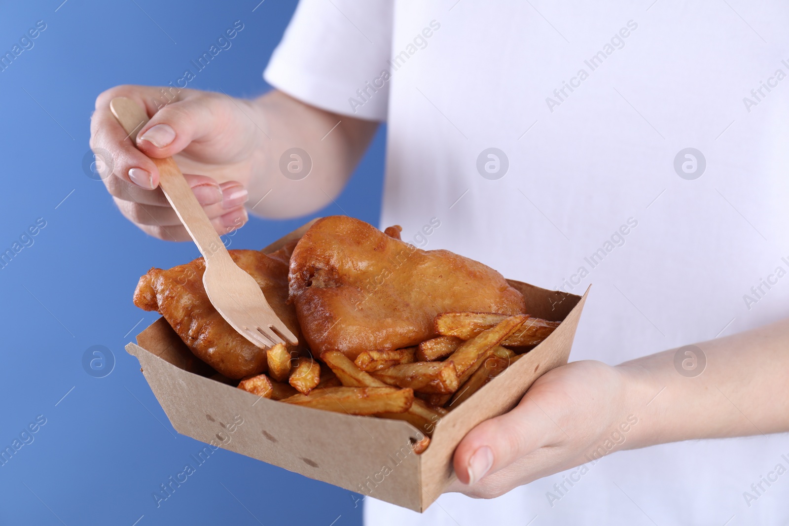 Photo of Woman eating fish and chips on blue background, closeup