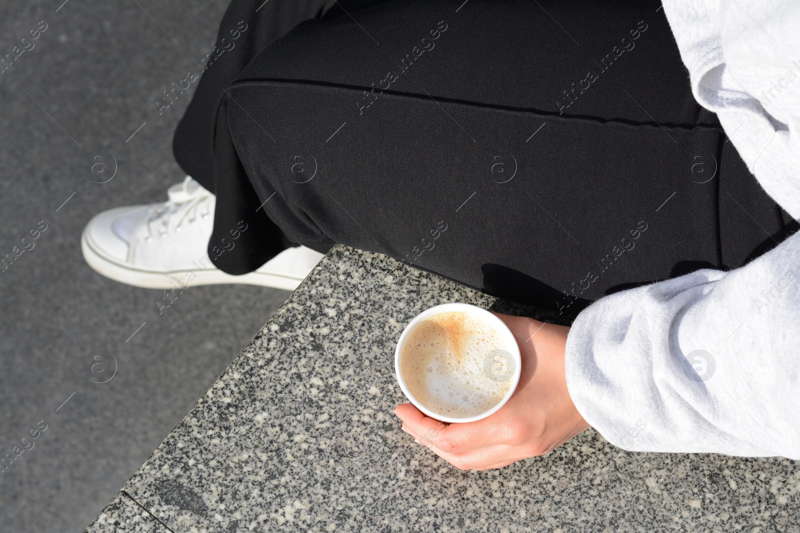 Photo of Woman sitting with cardboard cup of coffee outdoors, above view