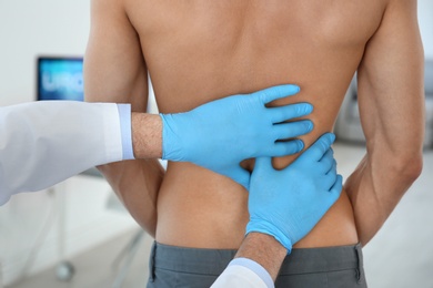 Urologist in gloves examining young patient in clinic