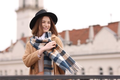 Photo of Beautiful woman in warm scarf and hat outdoors, space for text