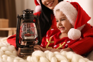 Mother and daughter playing with decorative snow globe at home, closeup